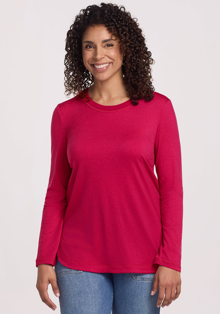Smiling person in the Woolx Hazel Tunic • Final Sale - Poppy Spark and blue jeans, standing against a plain background.