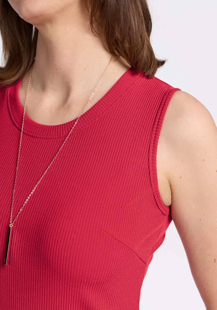 Woman in Woolx Iris Ribbed Dress - Berry Ice Pop, sleeveless ribbed knit, with a gold necklace and black pendant.