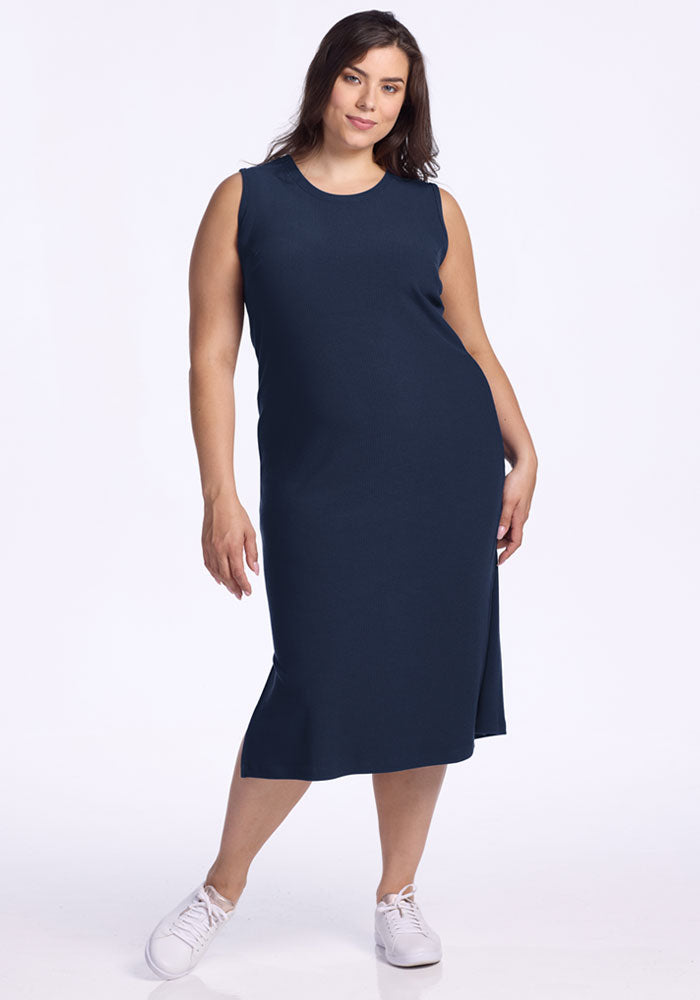 Woman wears the Woolx Iris Ribbed Dress in Deep Navy and white sneakers, posing on a plain white background.