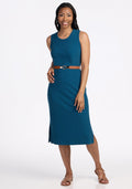 Woman in a Woolx Iris Ribbed Dress in Moroccan Blue, standing and smiling against a plain white background.