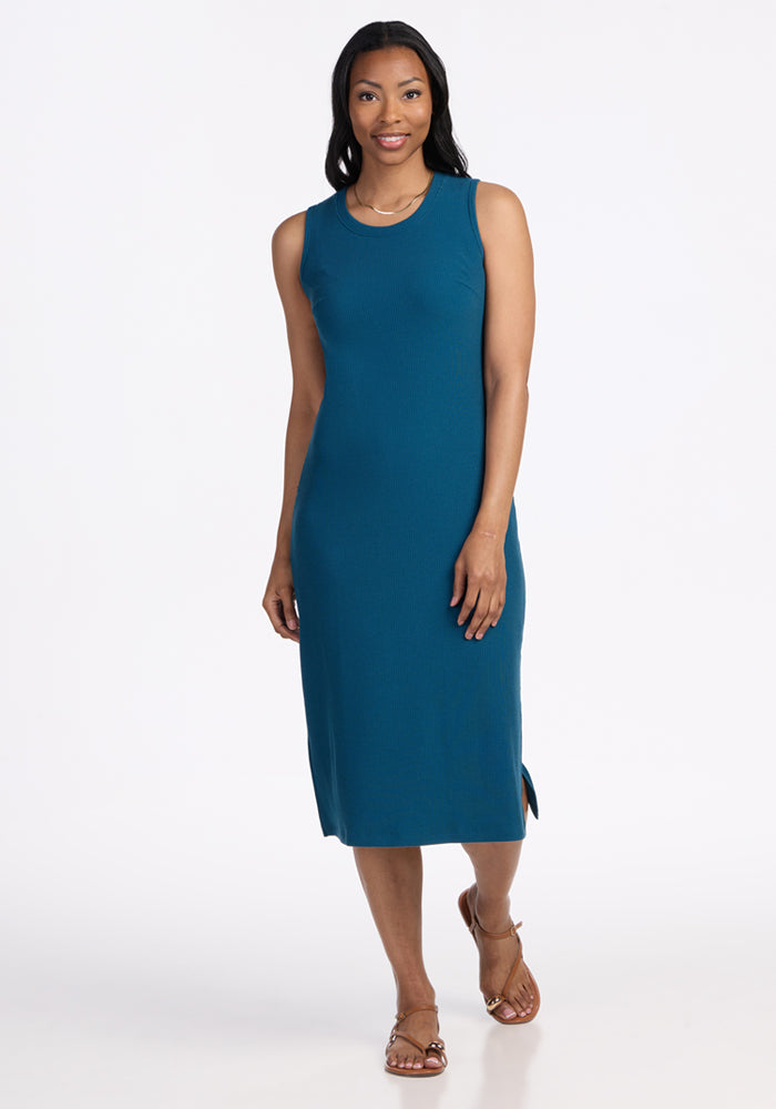 Woman wears the Woolx Iris Ribbed Dress in Moroccan Blue, smiling while standing against a plain white background.
