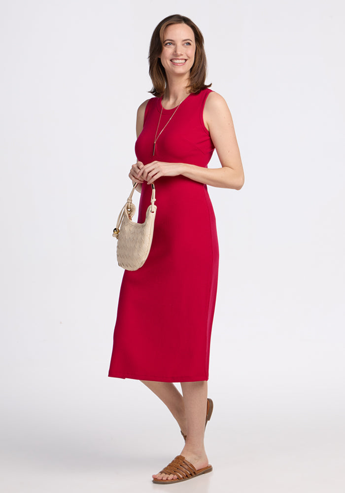 Smiling woman in Woolx Iris Ribbed Dress • Final Sale - Poppy Spark, holding beige purse, sandals on, white background.