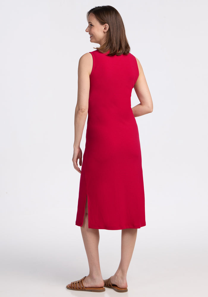 Woman in the Woolx Iris Ribbed Dress – Poppy Spark, sleeveless with side slits, smiling and seen from the back.