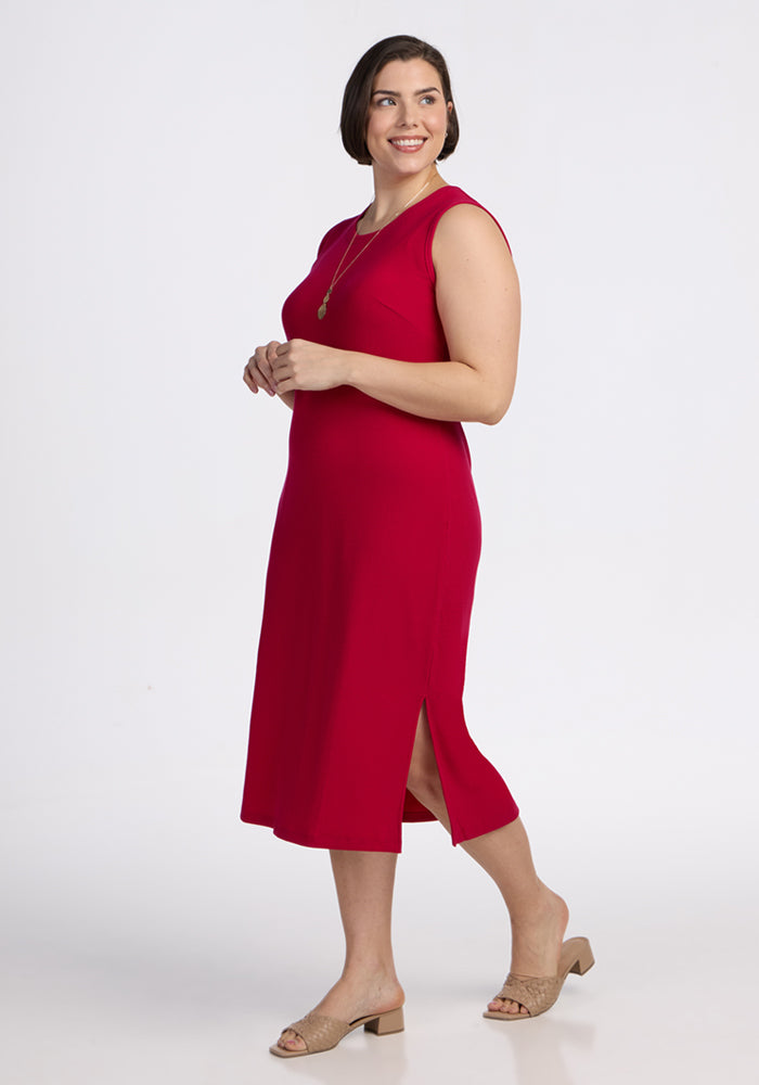 Woman in Woolx Iris Ribbed Dress in Poppy Spark, sleeveless with side slit, smiling in beige heeled sandals.