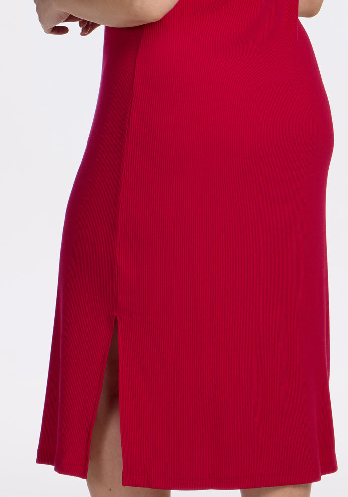 A person models the Woolx Iris Ribbed Dress in Poppy Spark, a wrinkle-resistant wool style with side slit.