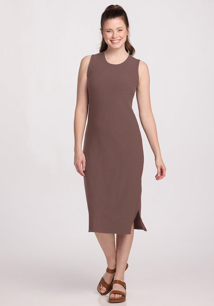 Woman in Woolx Iris Ribbed Dress in Peppercorn, sleeveless with side slit, smiling against a plain background. | Lilly is 5’9”, wearing a size S