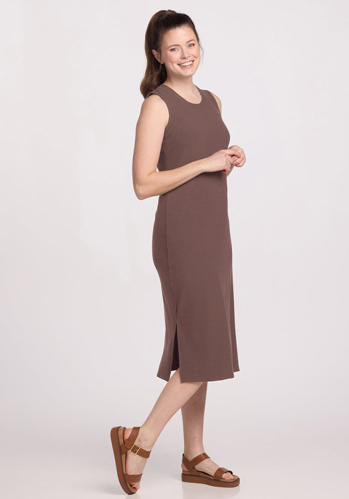 Woman smiles in the Woolx Iris Ribbed Dress - Peppercorn, wearing sandals, standing sideways on a white background.