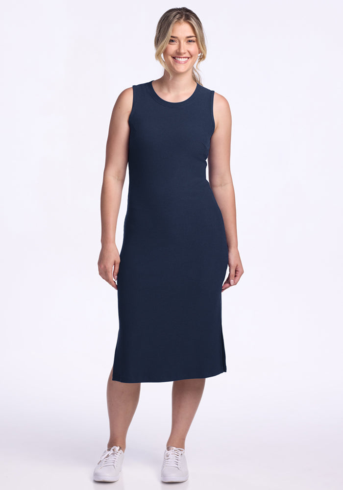 Smiling woman in the Woolx Iris Ribbed Dress in Deep Navy, standing against a plain white background.