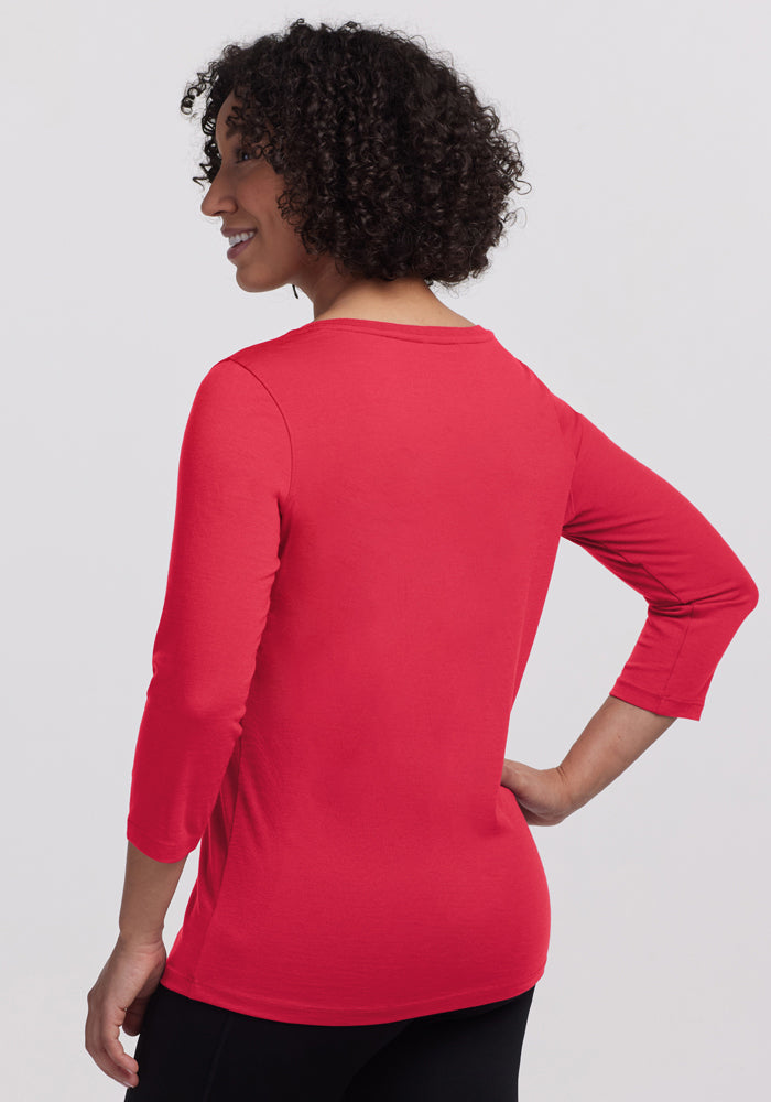 Woman with curly hair wears a Woolx Jenny 3/4 Sleeve Crew Neck in Berry Ice Pop, shown from the back.