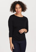 A person with curly hair wearing the Woolx Jenny 3/4 Sleeve Crew Neck in black smiles while standing against a white background, showcasing this versatile wardrobe staple. | Tori is 5'7", wearing a size S