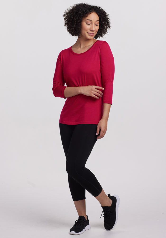 Woman wears Woolx Jenny 3/4 Sleeve Crew Neck in Poppy Spark, black leggings and sneakers, against a white background.