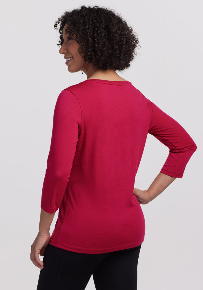 Person with curly hair, back to camera, wearing Woolx Jenny 3/4 Sleeve Crew Neck in Poppy Spark and black pants.