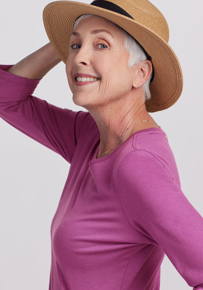 Smiling older woman in a straw hat wears the Woolx Jenny 3/4 Sleeve Crew Neck in Purple Wine, posing simply.