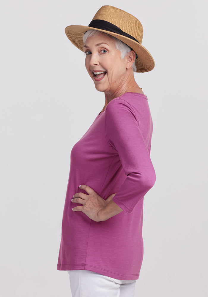 Woman in a straw hat models the Woolx Jenny 3/4 Sleeve Crew Neck in Purple Wine, smiling over her shoulder.