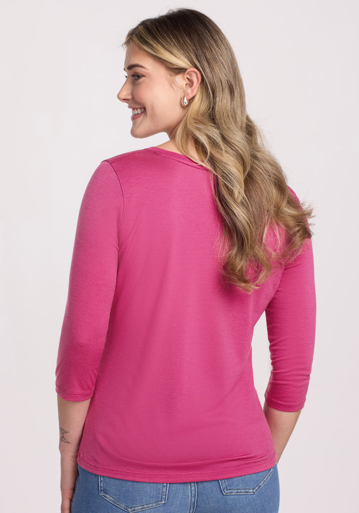 Smiling woman with long wavy hair wears the Woolx Jenny 3/4 Sleeve Crew Neck in Raspberry Fizz, back to camera.