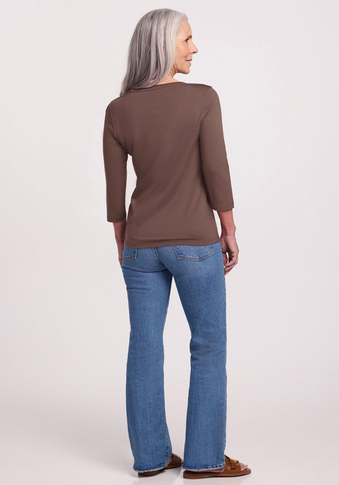 An older woman with long gray hair wears the Woolx Jenny 3/4 Sleeve Crew Neck in Peppercorn and blue jeans, facing away.