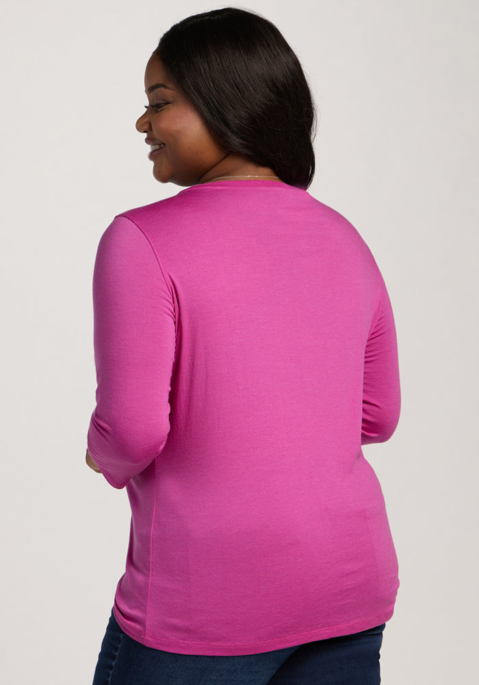 A woman faces away, showing the back of her Woolx Jenny 3/4 Sleeve Crew Neck in Summer Sorbet against a plain background.