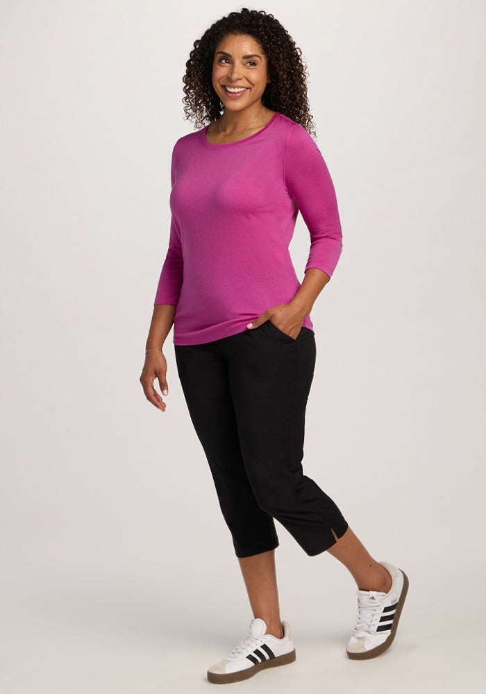 Woman with curly hair in the Woolx Jenny 3/4 Sleeve Crew Neck - Summer Sorbet, black capris, and white sneakers.