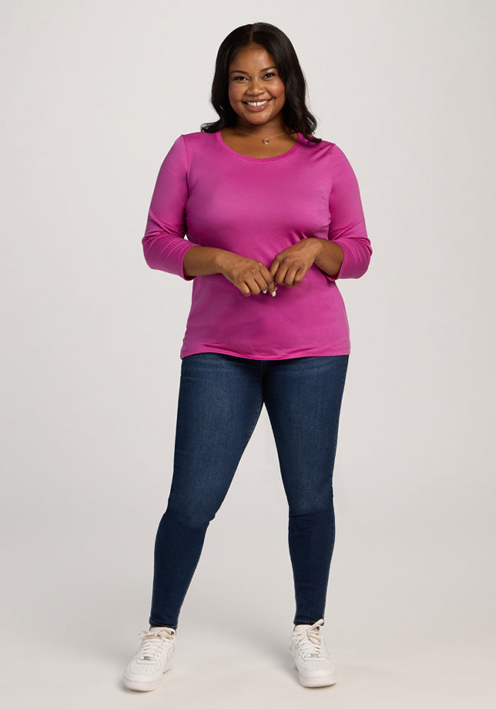 Woman smiling in a Woolx Jenny 3/4 Sleeve Crew Neck in Summer Sorbet, blue jeans, and white sneakers.