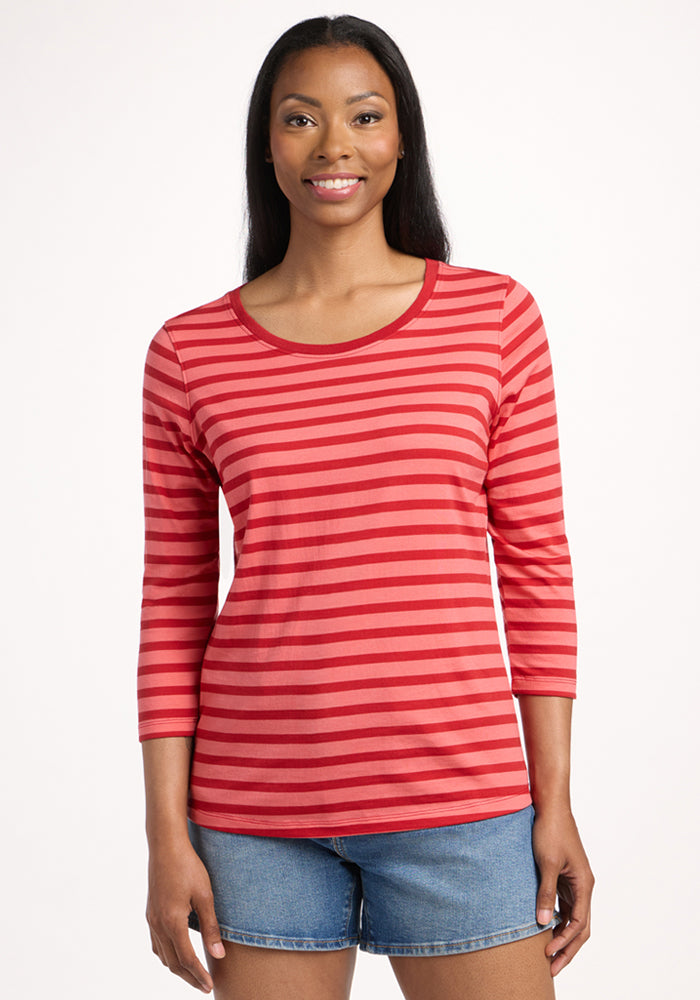 A woman smiles at the camera, wearing the Woolx Jenny 3/4 Sleeve Crew Neck in Wildberry Stripe with blue denim shorts, standing against a plain white background. | Jade is 5’10”, wearing a size S