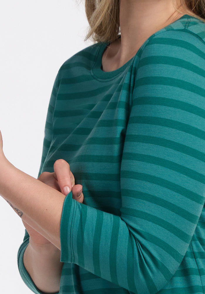 A person wearing a Woolx Jenny 3/4 Sleeve Crew Neck in Woodland Stripe is folding up one sleeve. The cropped image focuses on the upper body and arms.