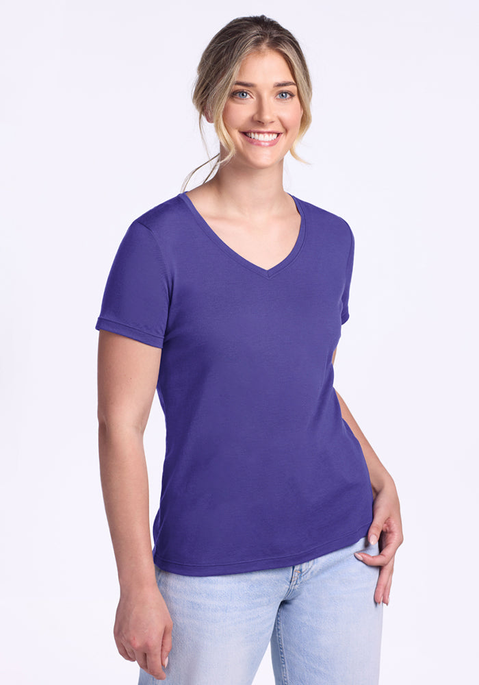 Smiling woman in the Woolx Junie V Neck - Berry Indigo, relaxed fit, and light jeans against a plain white background. | Ariana is 5'11", wearing a size S