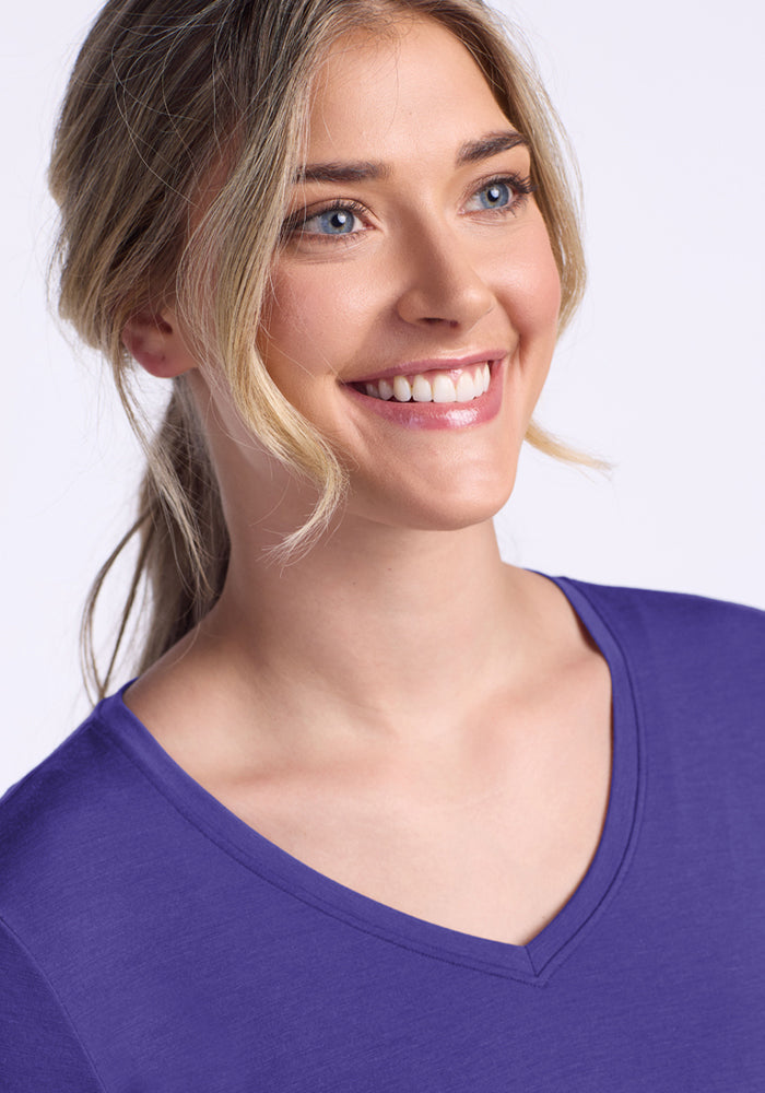 Smiling blonde woman in the Woolx Junie V Neck - Berry Indigo, looking to the side against a light background.