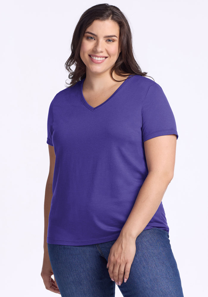 Woman smiling in the Woolx Junie V Neck - Berry Indigo, relaxed fit, paired with blue jeans against a light background. | Juliana is 5'10", wearing a size XL