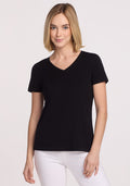 A woman with blonde, shoulder-length hair wears the Woolx Junie V Neck in black and white pants, standing against a plain light background and smiling slightly.