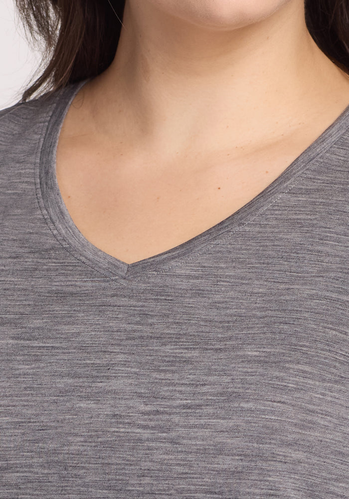 Close-up of a person wearing the Woolx Junie V Neck in Graphite Heather. Only the lower face, neck, and upper chest are shown. The Merino wool tee has a soft, textured look and offers natural odor resistance.