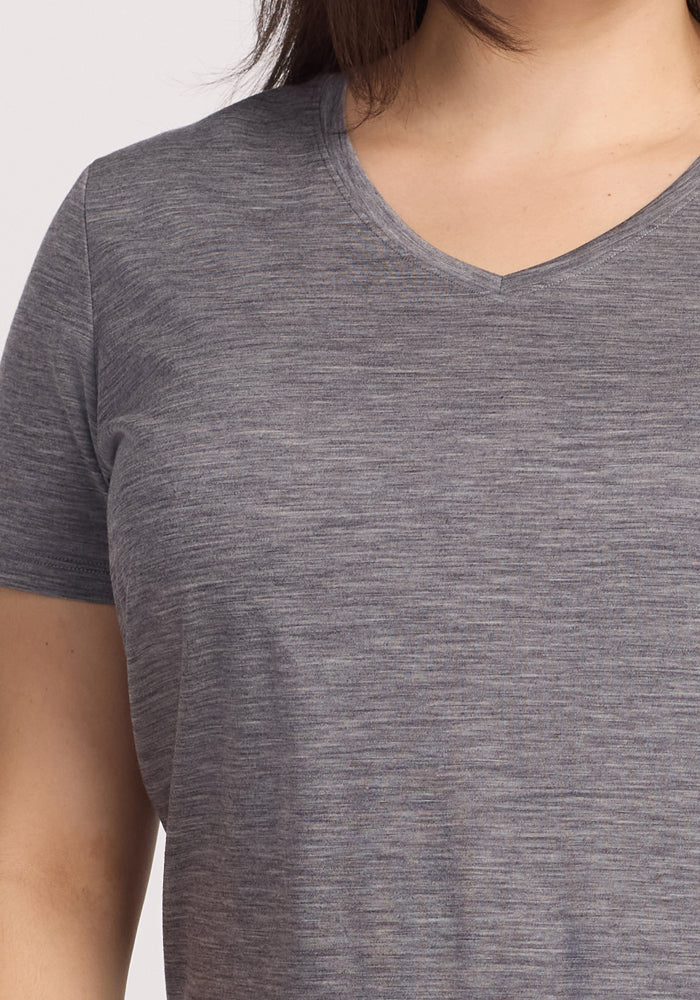 A woman wears the Woolx Junie V Neck in Graphite Heather. The image, cropped to show her upper torso and one arm, highlights the tee’s relaxed fit and moisture-wicking Merino wool fabric.