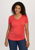 Smiling woman wears Woolx Junie V Neck - Hibiscus and blue jeans, standing against a plain light background. | Kisha is 5’8”, wearing a size M