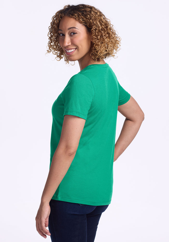 Smiling woman wearing the Woolx Junie V Neck - Jungle, posing with her back turned and looking over her shoulder.