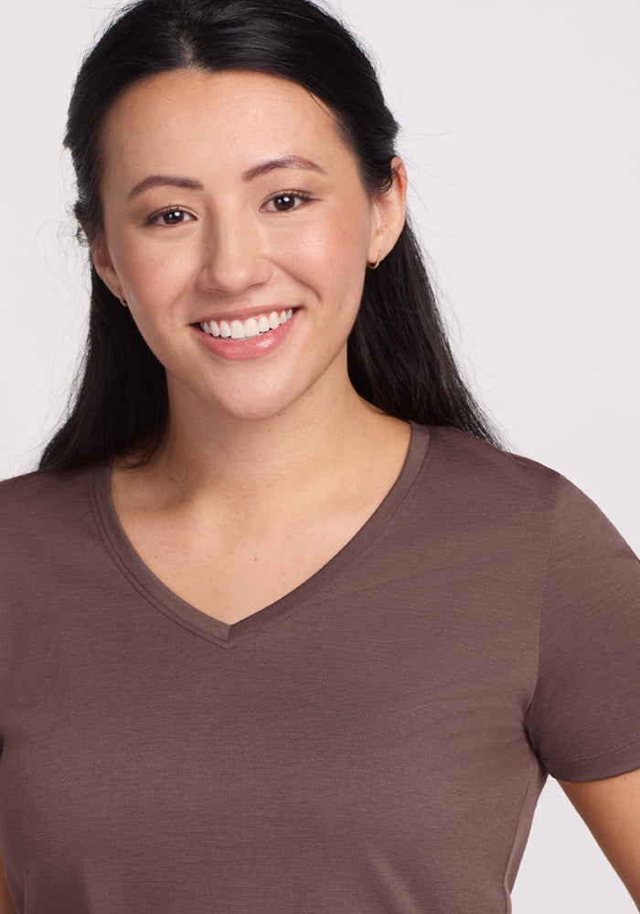 Smiling woman in a Woolx Junie V Neck - Peppercorn tee, with long dark hair, against a plain light background.