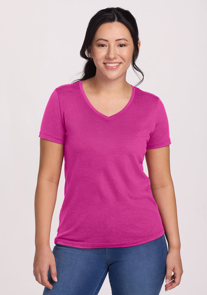 Woman smiles in a Woolx Junie V Neck - Summer Sorbet tee and blue jeans, against a plain light background. | Sarah is 5'8", wearing a size S