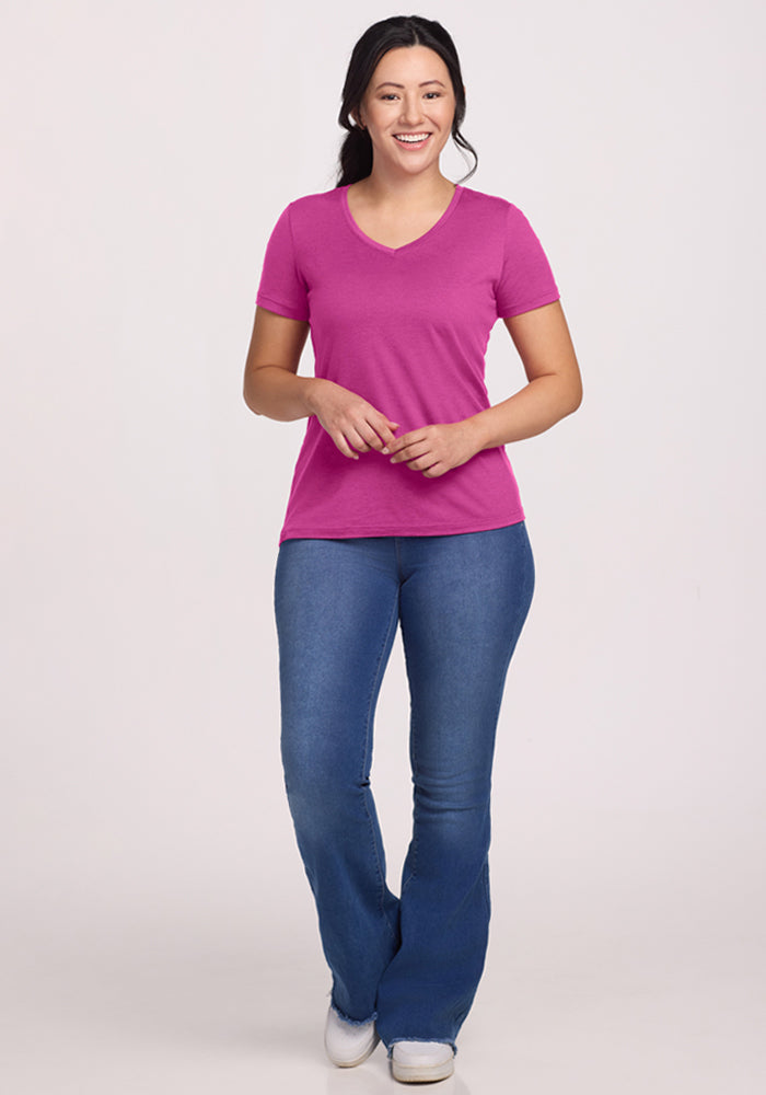 Smiling woman wears a relaxed fit Woolx Junie V Neck - Summer Sorbet tee with blue jeans against a light background.