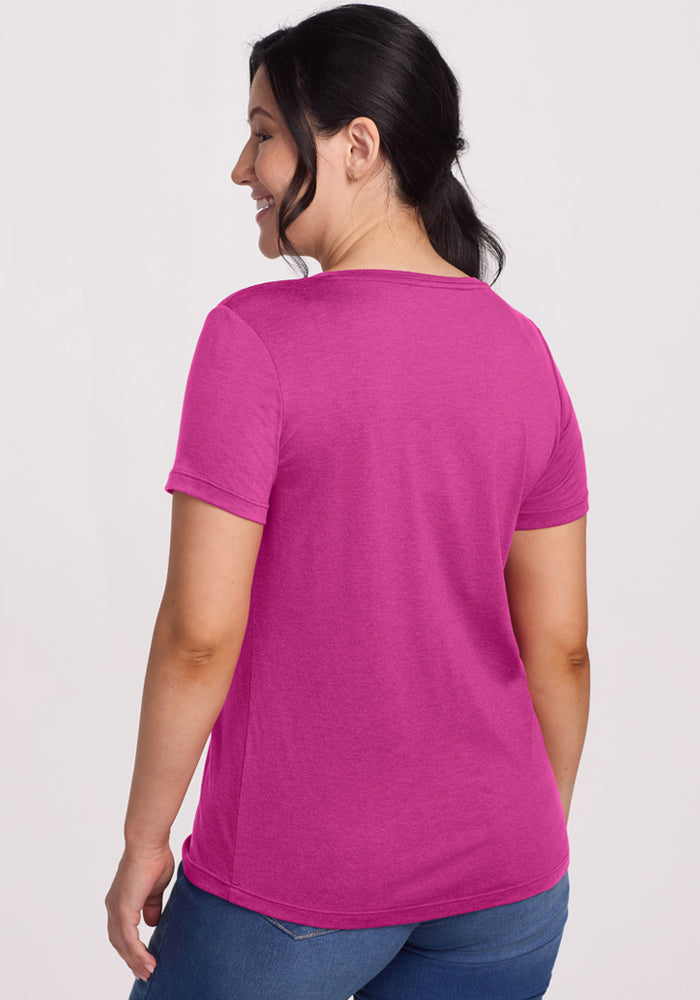 Woman with dark hair in ponytail wears a Woolx Junie V Neck - Summer Sorbet, relaxed fit, with jeans, smiling away.