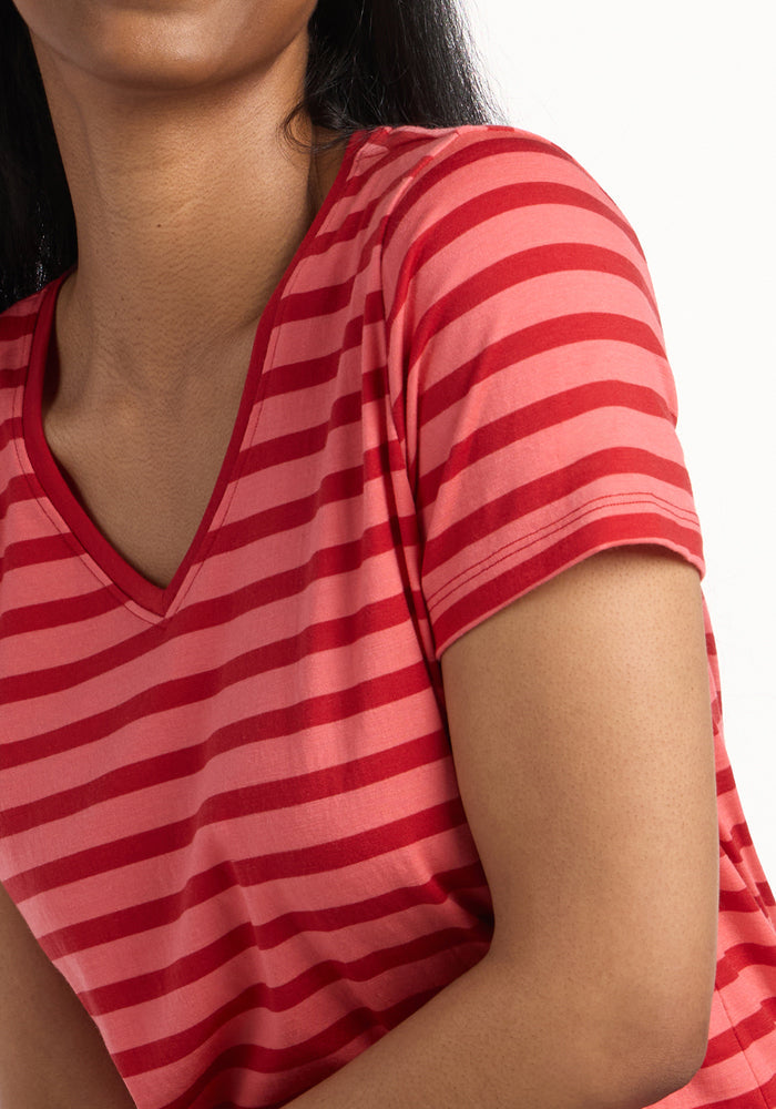 A person with medium-toned skin and long, dark hair models the Woolx Junie V Neck - Wildberry Stripe, showing their upper torso and part of their face against a white background.
