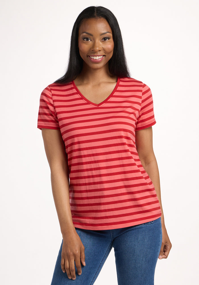 A woman with long dark hair smiles while wearing the Woolx Junie V Neck in Wildberry Stripe and blue jeans, standing against a plain white background. | Jade is 5’10”, wearing a size S