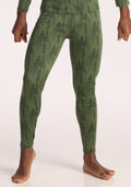 A child stands barefoot, shown from the shoulders down against a pale background, wearing Woolx Kids Explorer Base Layer Bottoms in the Forest Friends color. Their fists are gently clenched at their sides. | Banyan is wearing a size LRG.