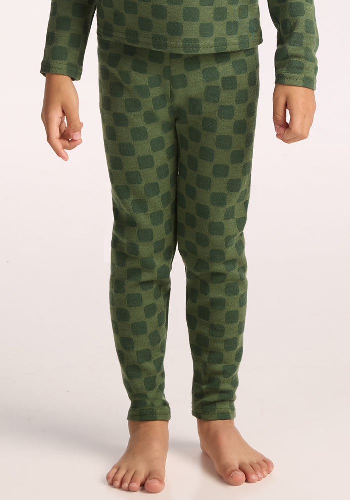 A child stands barefoot, wearing Woolx Kids Explorer Base Layer Bottoms - Frog Hop and a matching long-sleeve top with a dark green checkered pattern; only the body from shoulders down is visible. | Leo is wearing a size XSM.