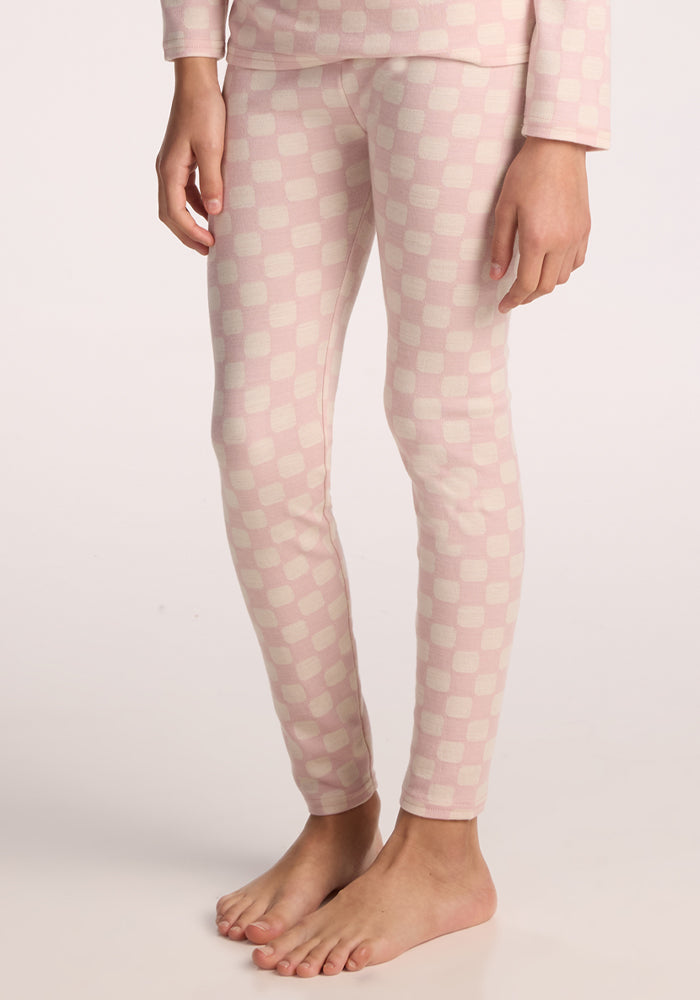 A child stands barefoot in Woolx Kids Explorer Base Layer Bottoms in Hopscotch Pink, with their body shown from shoulders to feet against a plain light background. | Hanna is wearing a size LRG.