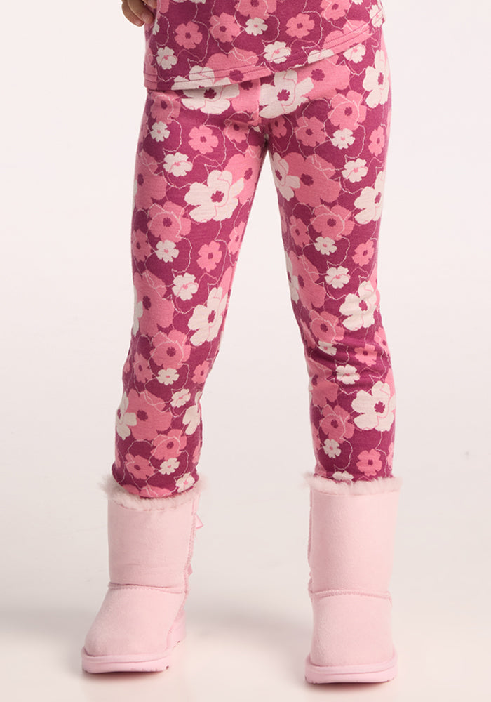 A child stands against a plain background, showing only their lower half, and wears Woolx Kids Explorer Base Layer Bottoms - Rosie Posie with light pink, fur-trimmed boots. | Aria is wearing a size SML.