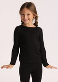 A smiling young girl with light brown braids wears the black Woolx Kids Explorer Base Layer Top. She stands with arms slightly outstretched against a plain light background, showcasing the brand’s moisture-wicking merino wool design. | Aria is wearing a size XSM.