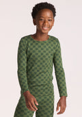 A smiling child wearing the Woolx Kids Explorer Base Layer Top in Frog Hop stands against a plain light background. | Banyan is wearing a size LRG.