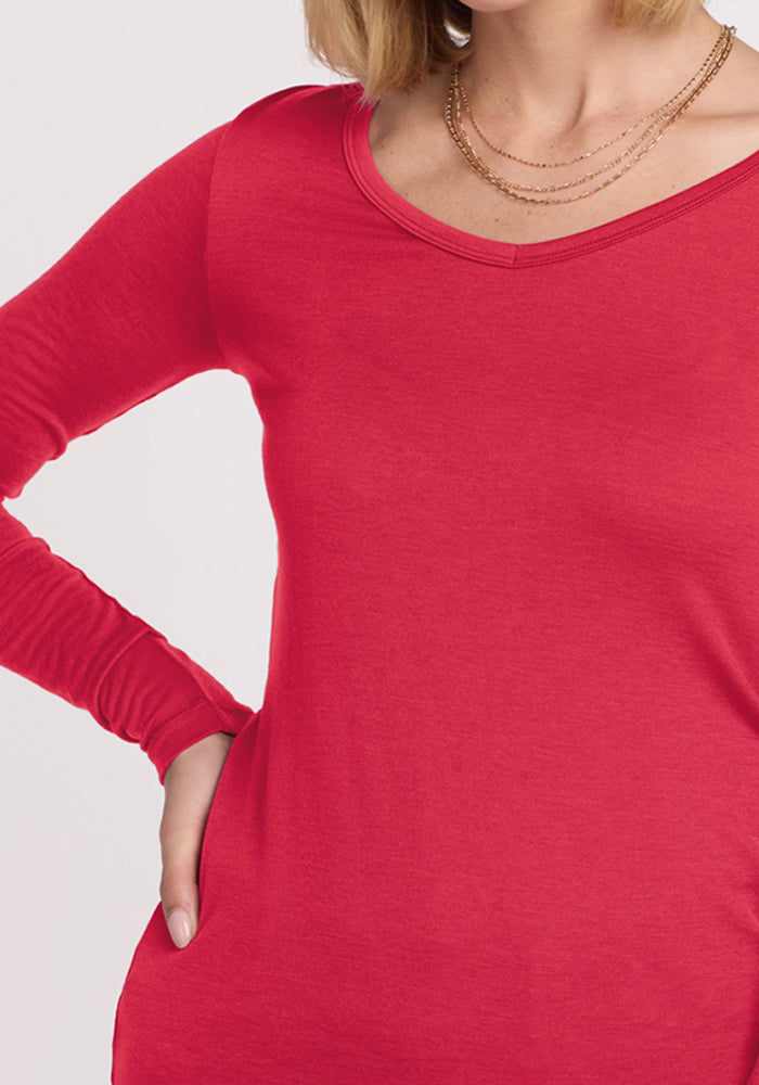 Woman in the Woolx Layla V Neck Top in Berry Ice Pop and layered gold necklaces, hand confidently on her hip.