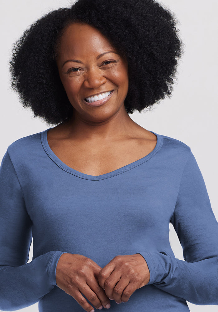 Smiling woman in Woolx Layla V Neck Top in Skyline, standing against a plain light background.