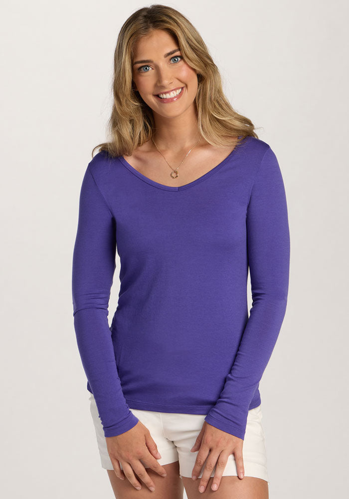 Woman with long hair in a Woolx Layla V Neck Top - Berry Indigo and white shorts, smiling against a plain background. | Ariana is 5'11", wearing a size S