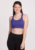 Woman smiling in a Woolx Livi Bra - Berry Indigo and black leggings, standing against a plain light background. | Lilly is 5’9”, wearing a size S