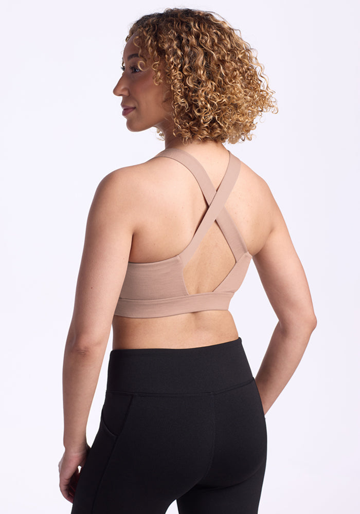 Woman with curly hair wears Woolx Livi Bra in Morning Latte, shown from the back against a white background.